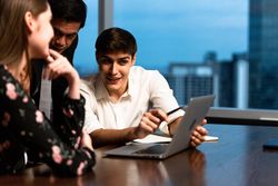Male employee presenting work from laptop to colleagues in meeting room