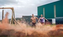 Athletes jumping finish line of an obstacle course