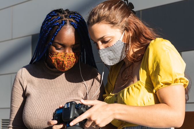 Cheerful multiethnic women looking through photos together