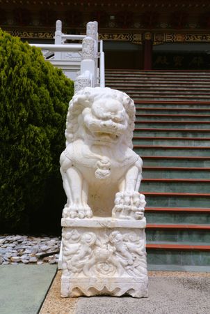 Lion statue guards the steps of a traditional temple in serene surroundings