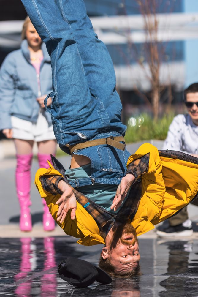 Vertical Screen: Young And Athletic B-Boy Breakdancing To Break Beats On The City Street In The Circle Of Friends.