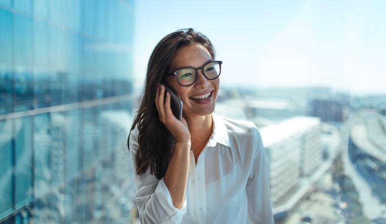 Beautiful woman talking on cell phone in high-rise office building