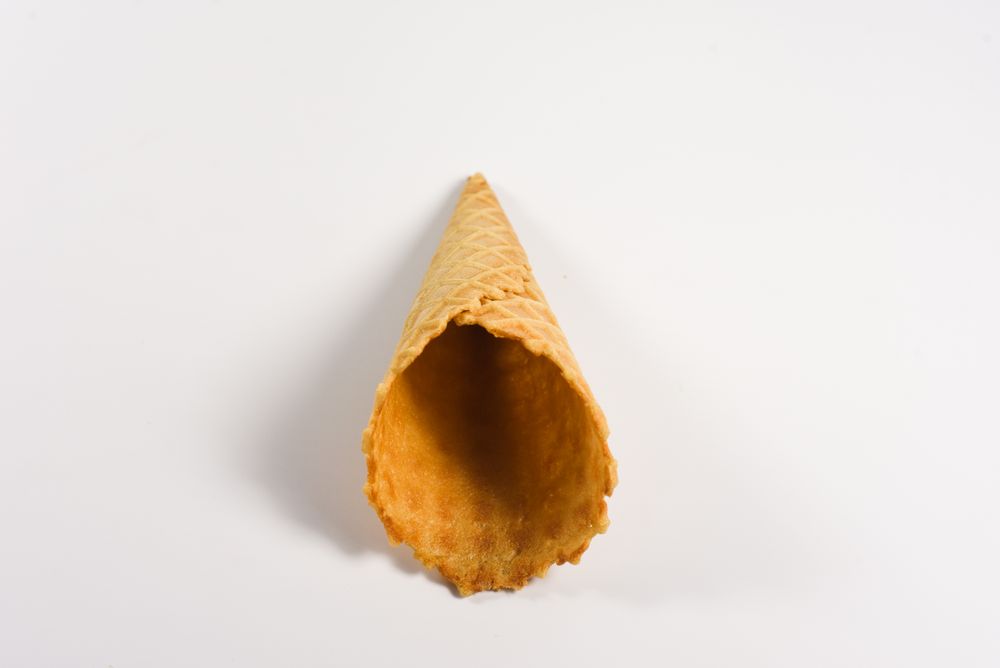 One empty waffle cone lying on plain table