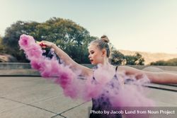 Young woman dancing outdoors with pink smoke bomb 49qmy4