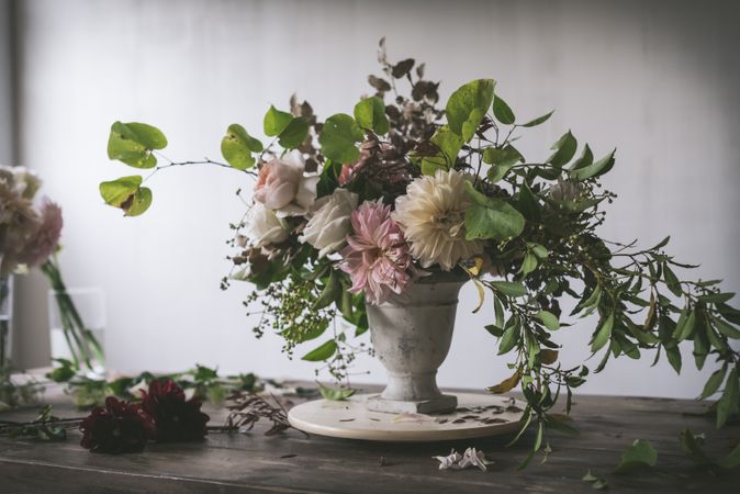 Composition of flowers and plants in vintage vase on board