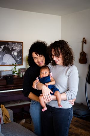 Two women with their curious baby girl at home, vertical