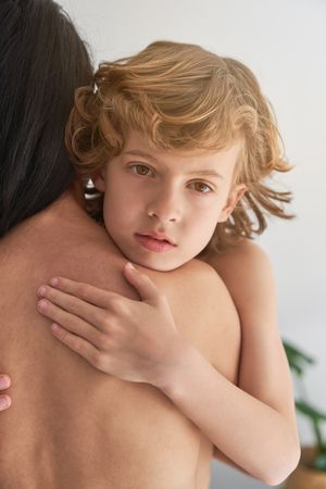 Boy embracing faceless topless mother