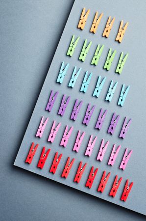 Rainbow colored clothes pins on gray background