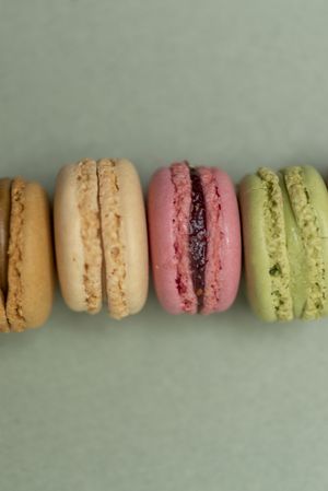 Line of colorful tasty macaroons over a green background, vertical