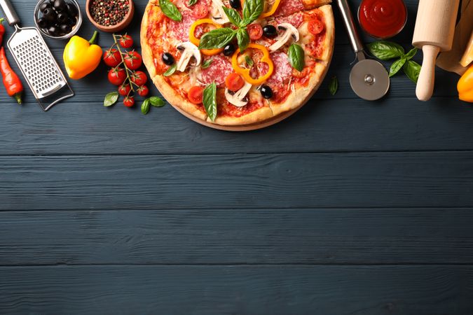 Delicious pizza and ingredients on wooden background, copy space