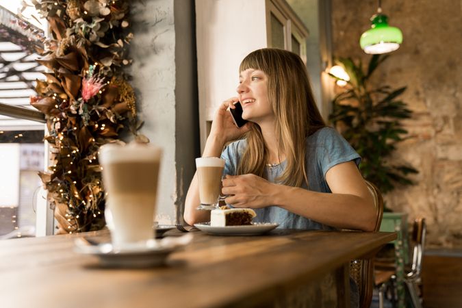 Cheerful woman talking on phone in cafe