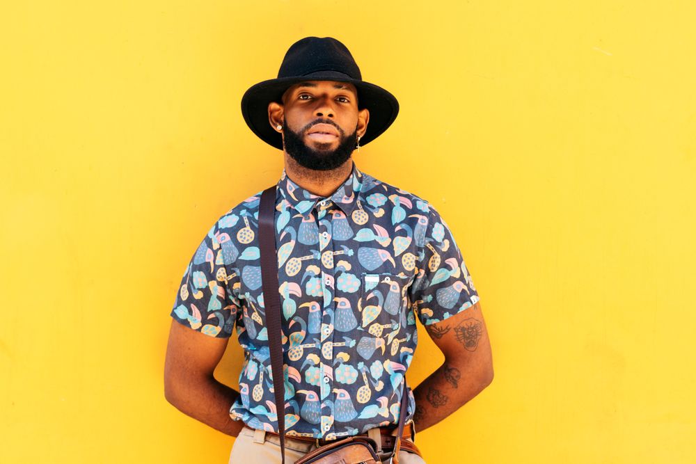 Stylish Black man outdoors over yellow background