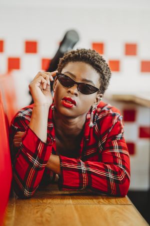 Gorgeous stylish Black woman in sunglasses in cafe