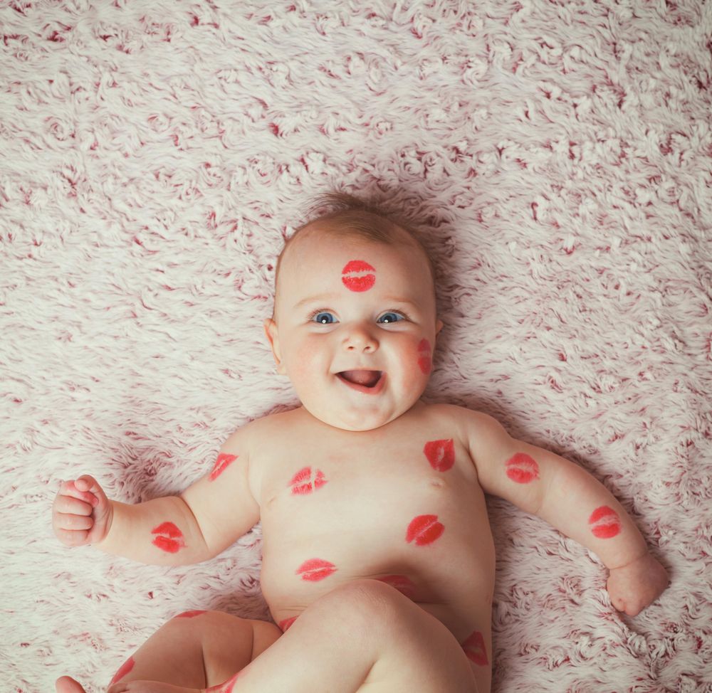 Baby with lips print on his body smiling
