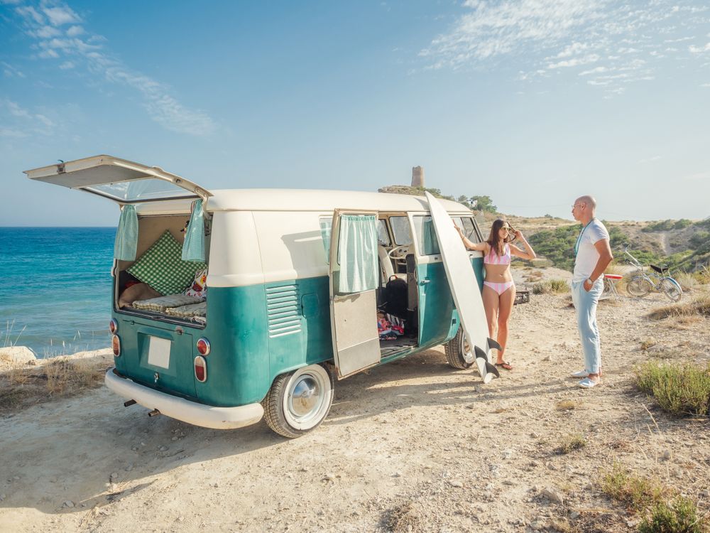Man and woman chatting leaning on trailer at seaside