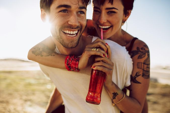 Young happy couple outdoors having fun with soda