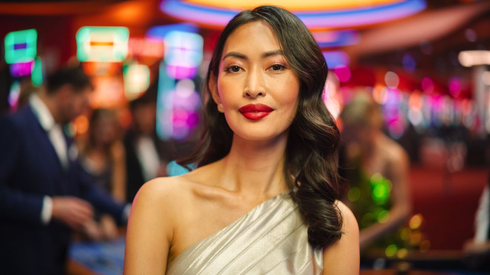 Young Asian Woman Standing in a Glamorous Atmosphere of a Casino, Looking at Camera.