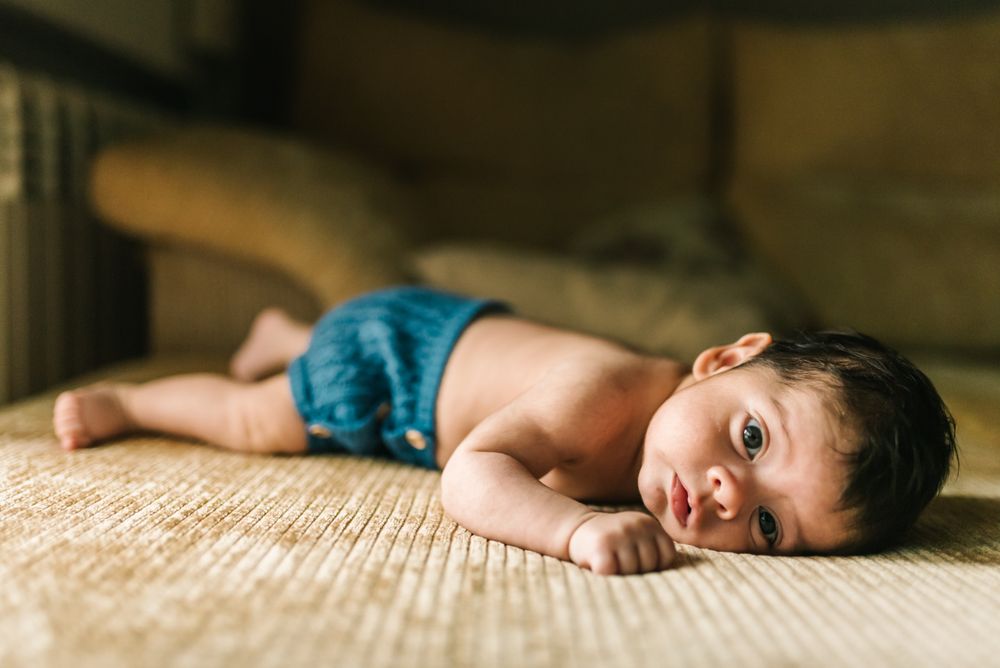 innocent newborn baby in back lying on sofa at home