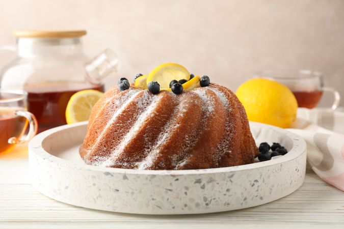 Cake with powder sugar and lemon on plain background, close up
