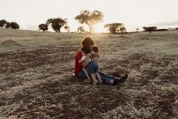 Mother sitting down holding both children in a field