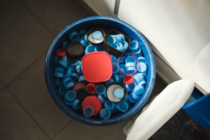Plastic bucket with bottle caps and container