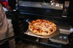 Pizza on a shovel fresh from the oven
