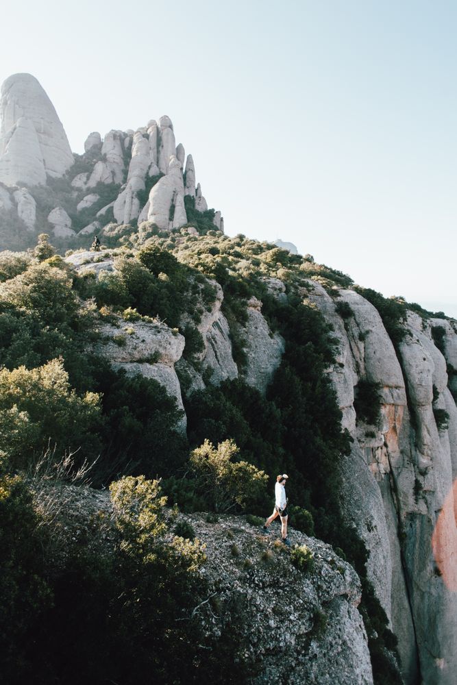 Man on top of shear rock face overlooking roadway