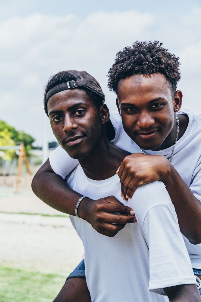Cheerful hugging Black young men looking at camera