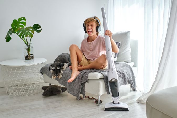 Boy with vacuum cleaner singing near dog