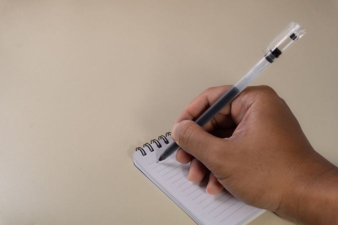 A hand writing with a ballpoint pen on an open notebook