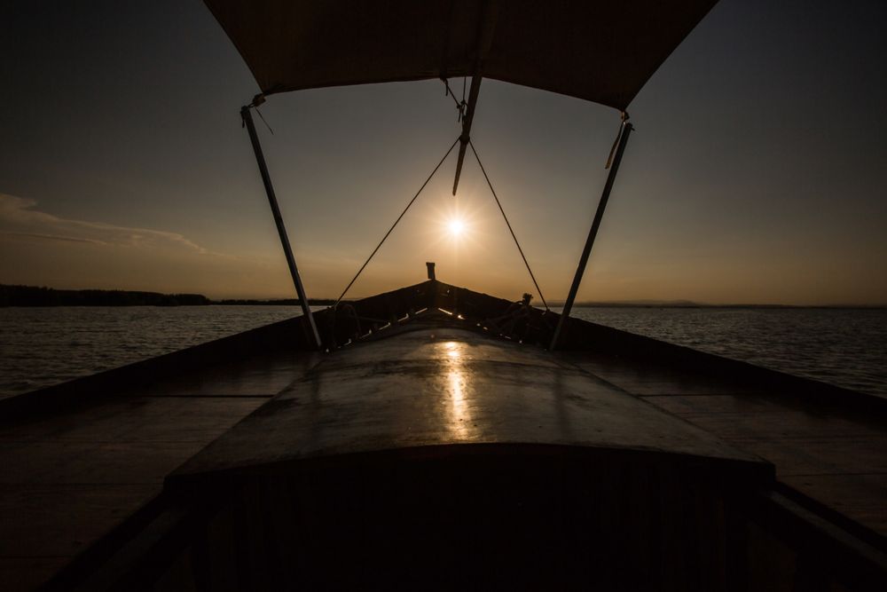 Front of boat riding along sea at twilight