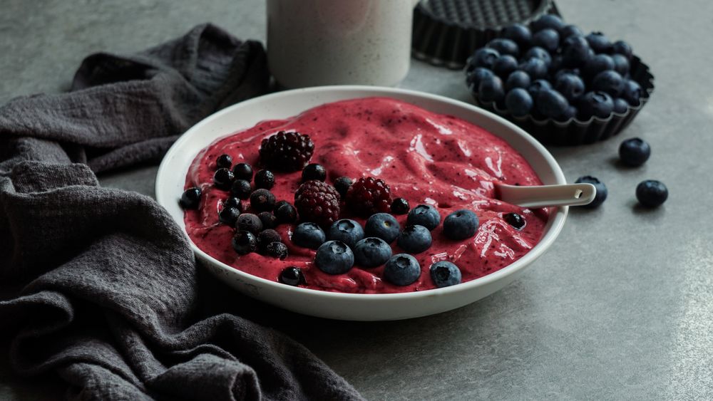 Smoothy of fresh bog blueberries and raspberries in bowl near napkin