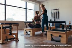 Rear view of a trainer guiding a woman doing pilates workout at the gym 416qZb