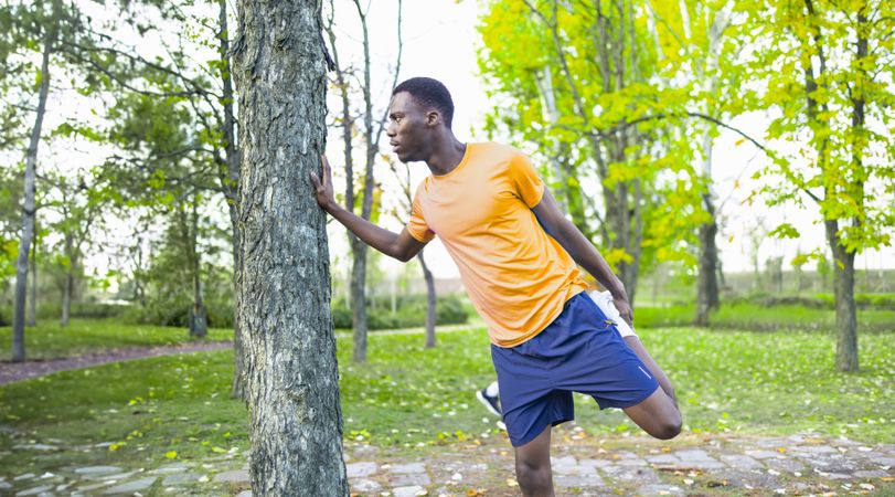 Young Black man stretching his leg before his morning workout.