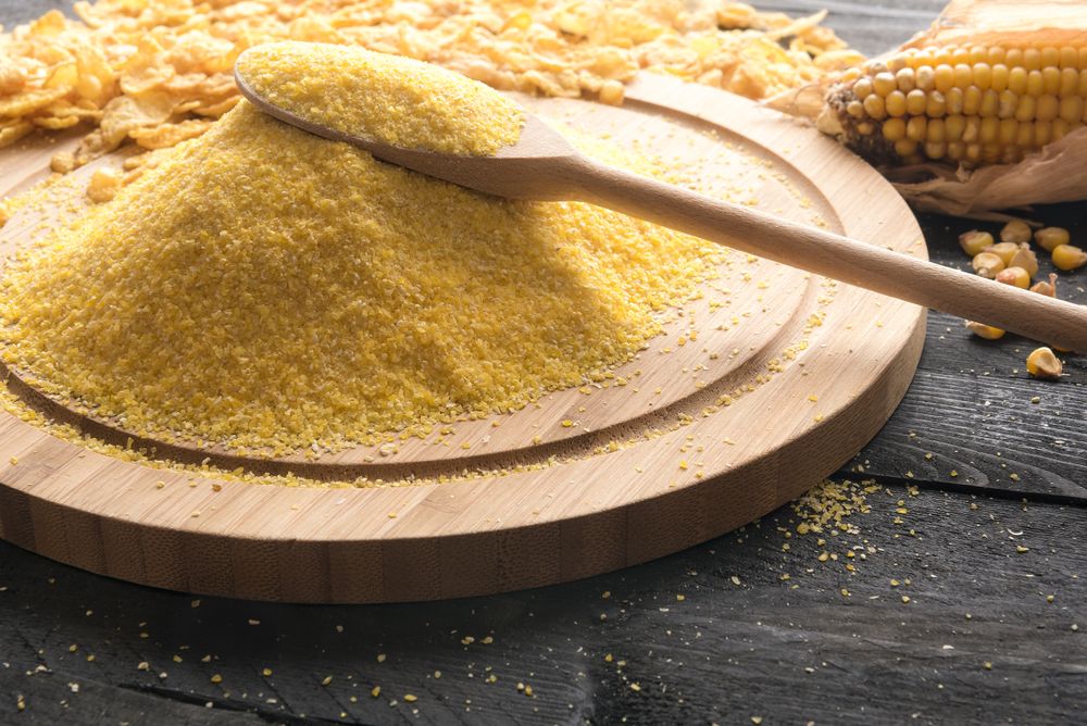 Pile of polenta on a wooden board on dark wooden background