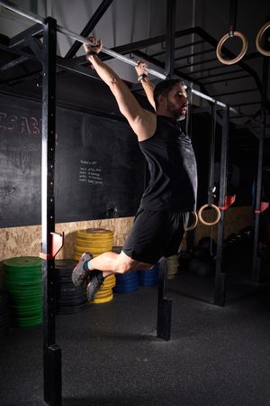 Muscular sportsman exercising on bar