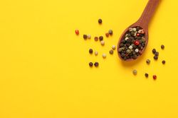 Top view of wooden spoon with whole peppercorns, copy space