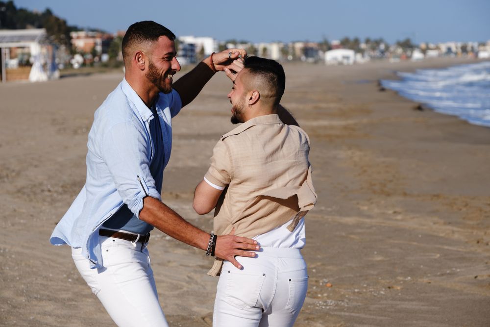Happy gay couple dancing on seaside