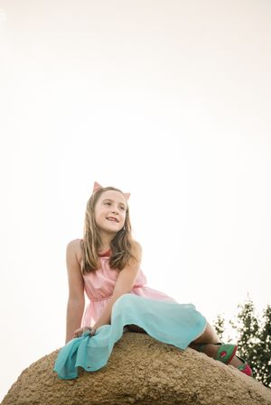 Dreamy cute girl sitting on rock