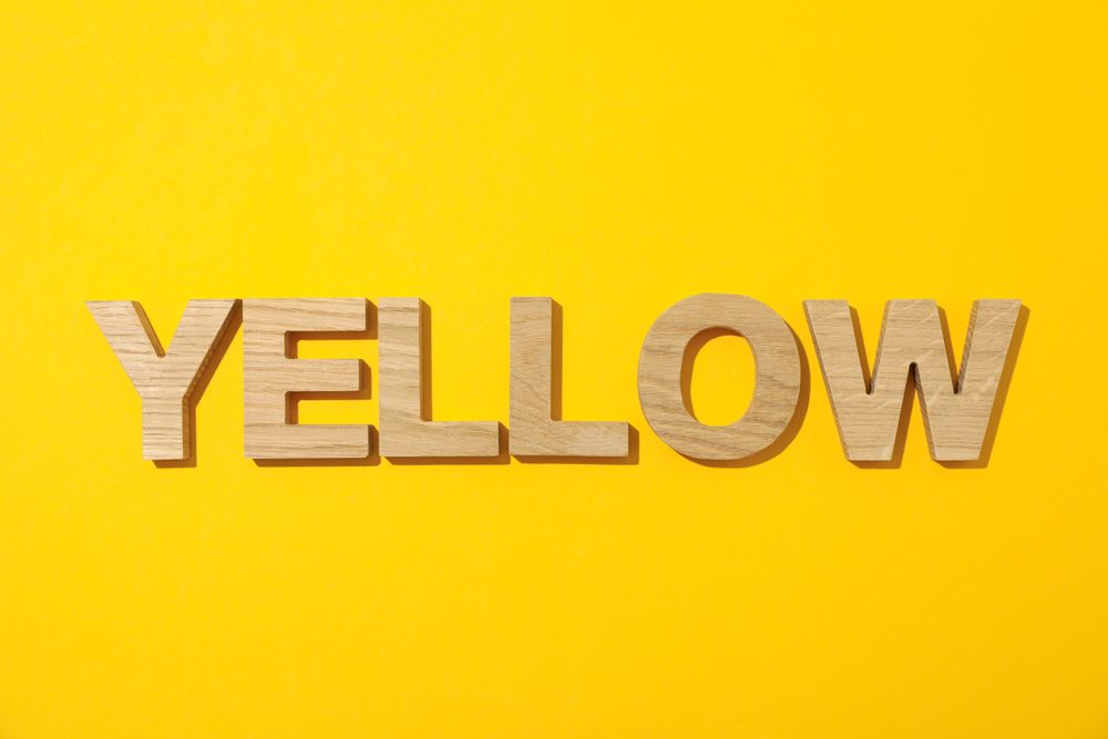 Word Yellow laid out in wooden letters on color background