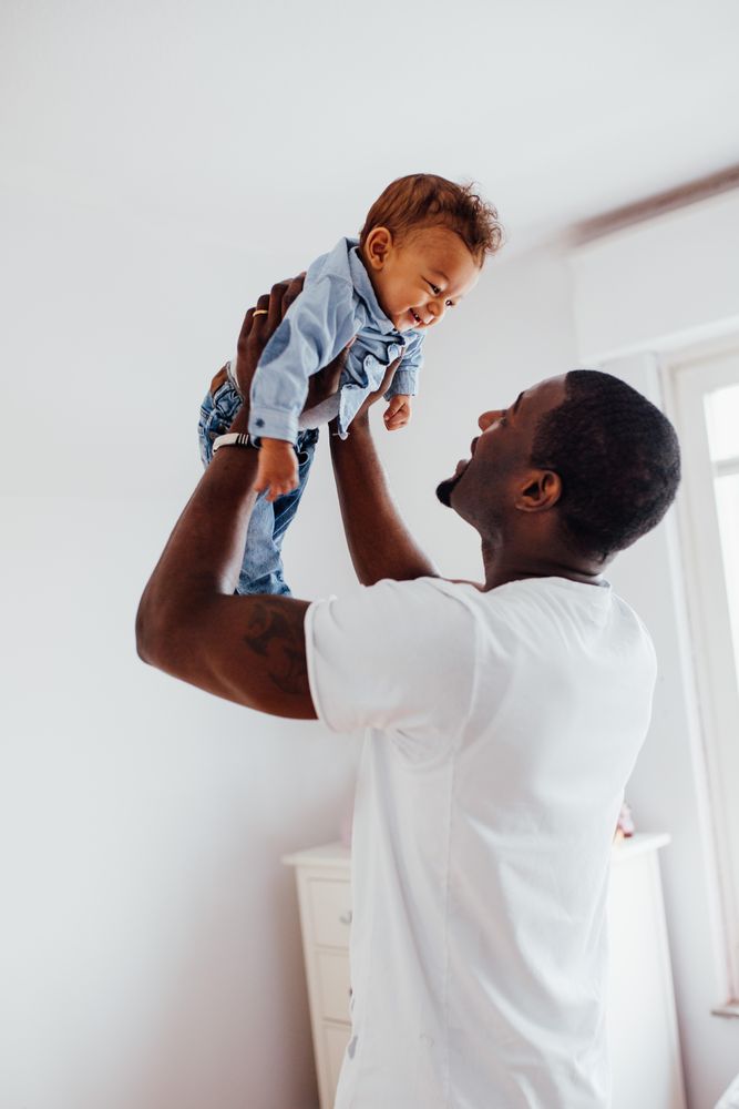 Baby boy smiling into his father face as he holds him