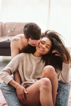 Multiethnic couple hugging on floor at home