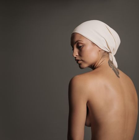Woman with bare back and scarf wrapped on her head in studio