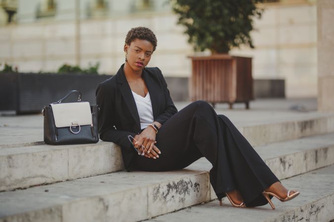 Stylish Black woman with handbag and sunglasses on steps