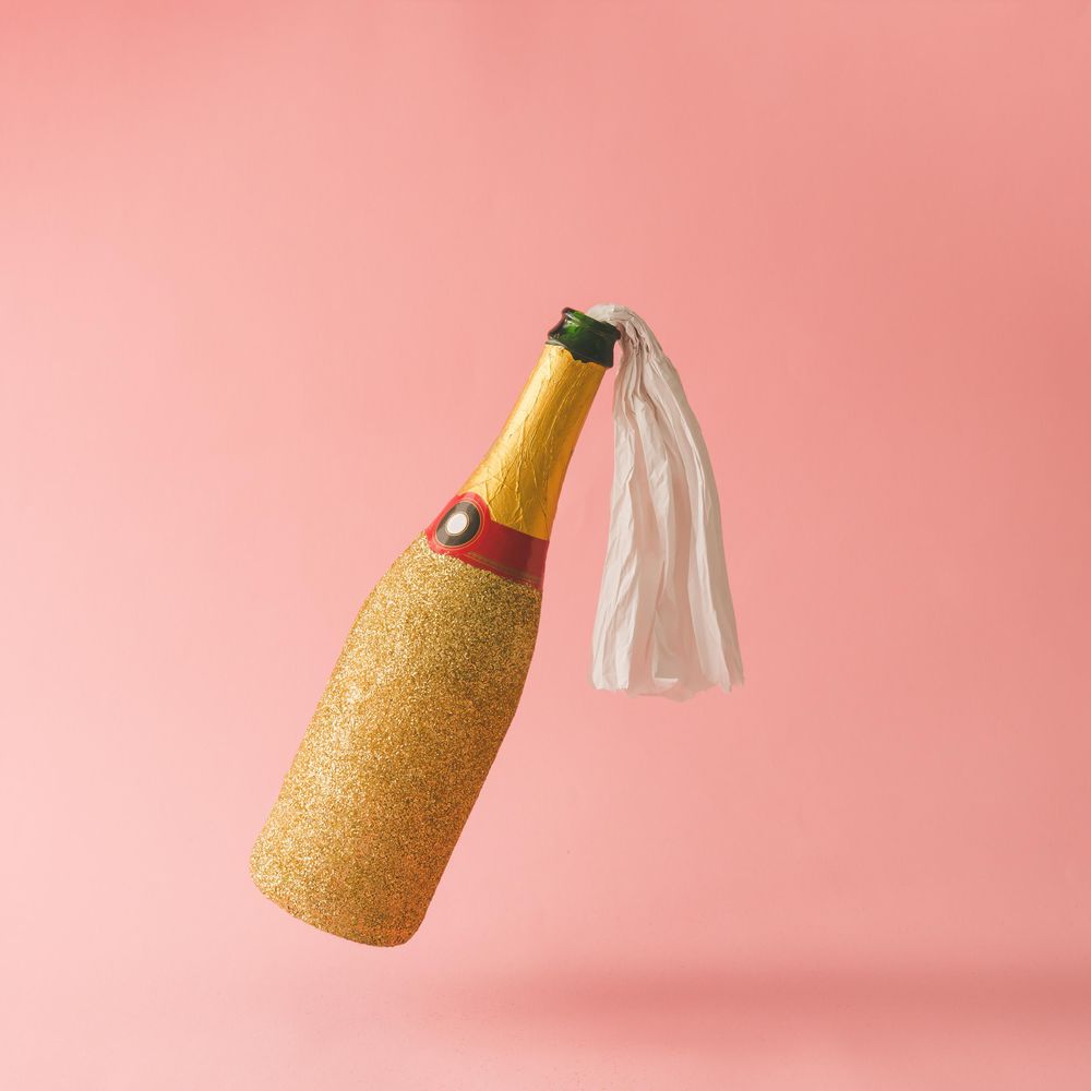 Molotov cocktail gold champagne bottle on pink background
