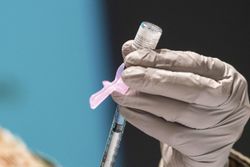A technician loads a syringe with the COVID-19 vaccine
