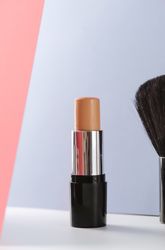 Concealer stick and make up brush on modern background