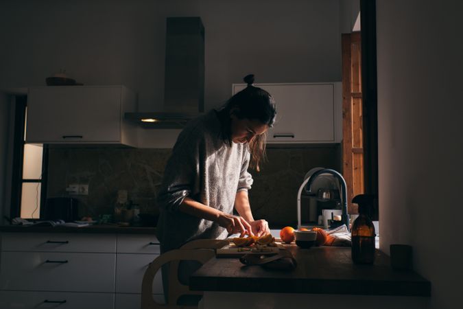 Woman cutting fruits on cutting board in kitchen
