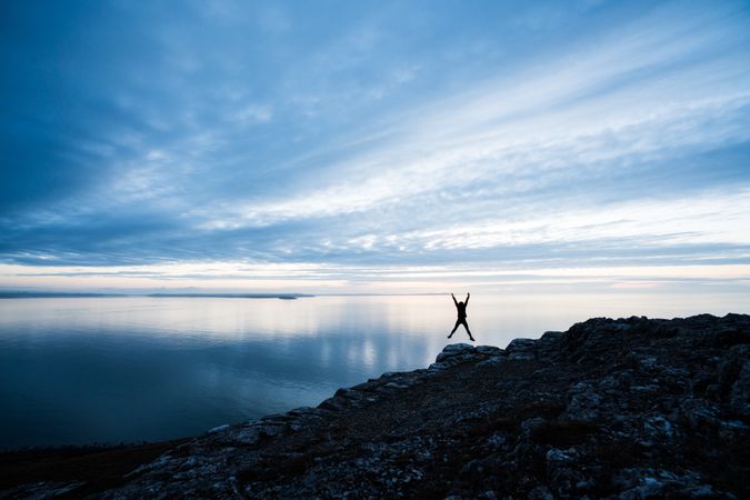 Happy man jumping on rocky coastline