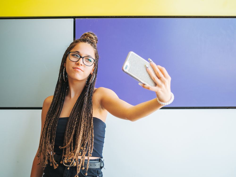 Woman with dreadlocks in glasses taking selfie